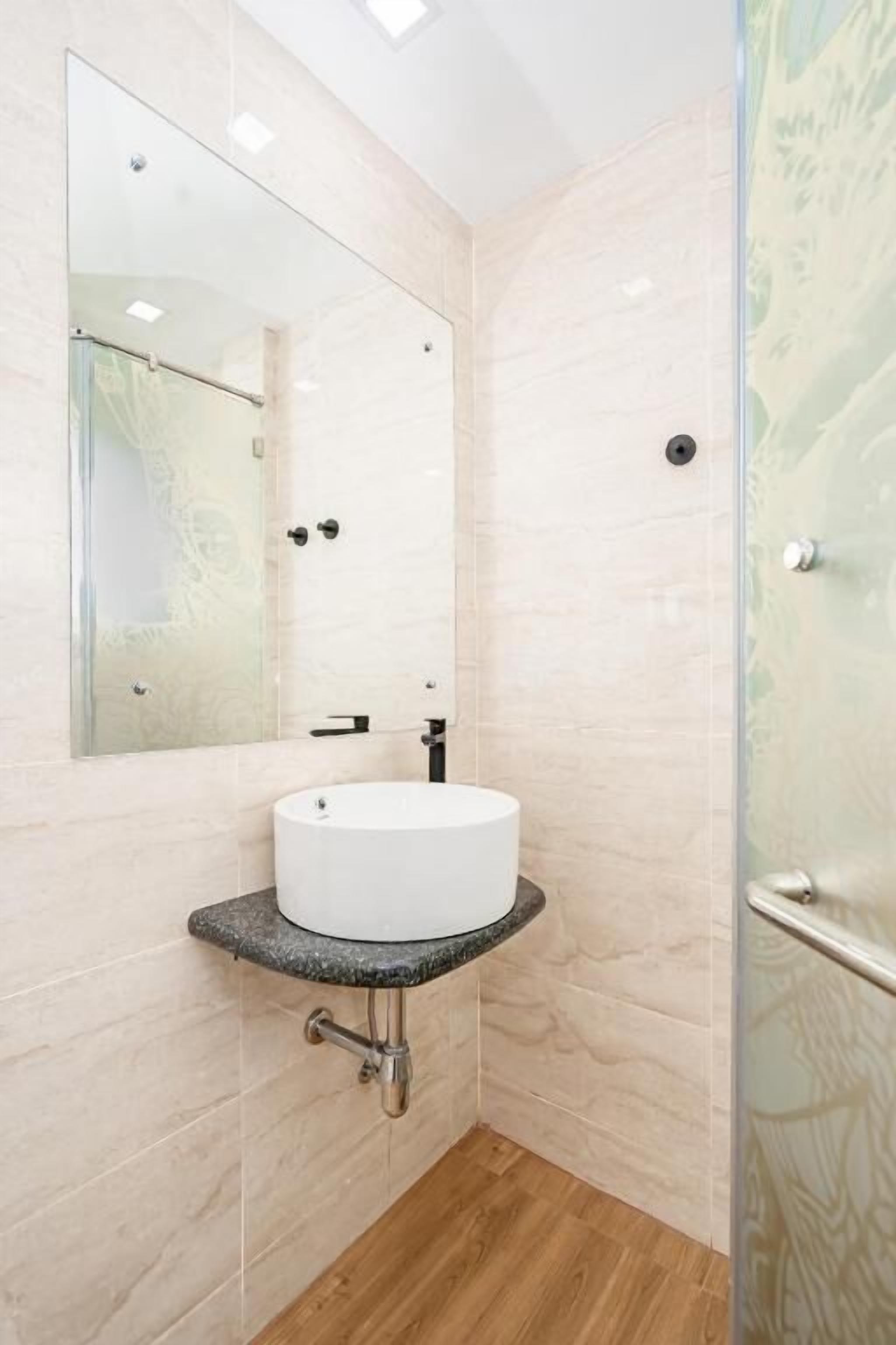 Un baño con lavamanos blanco, un espejo grande y una cabina de ducha de vidrio.