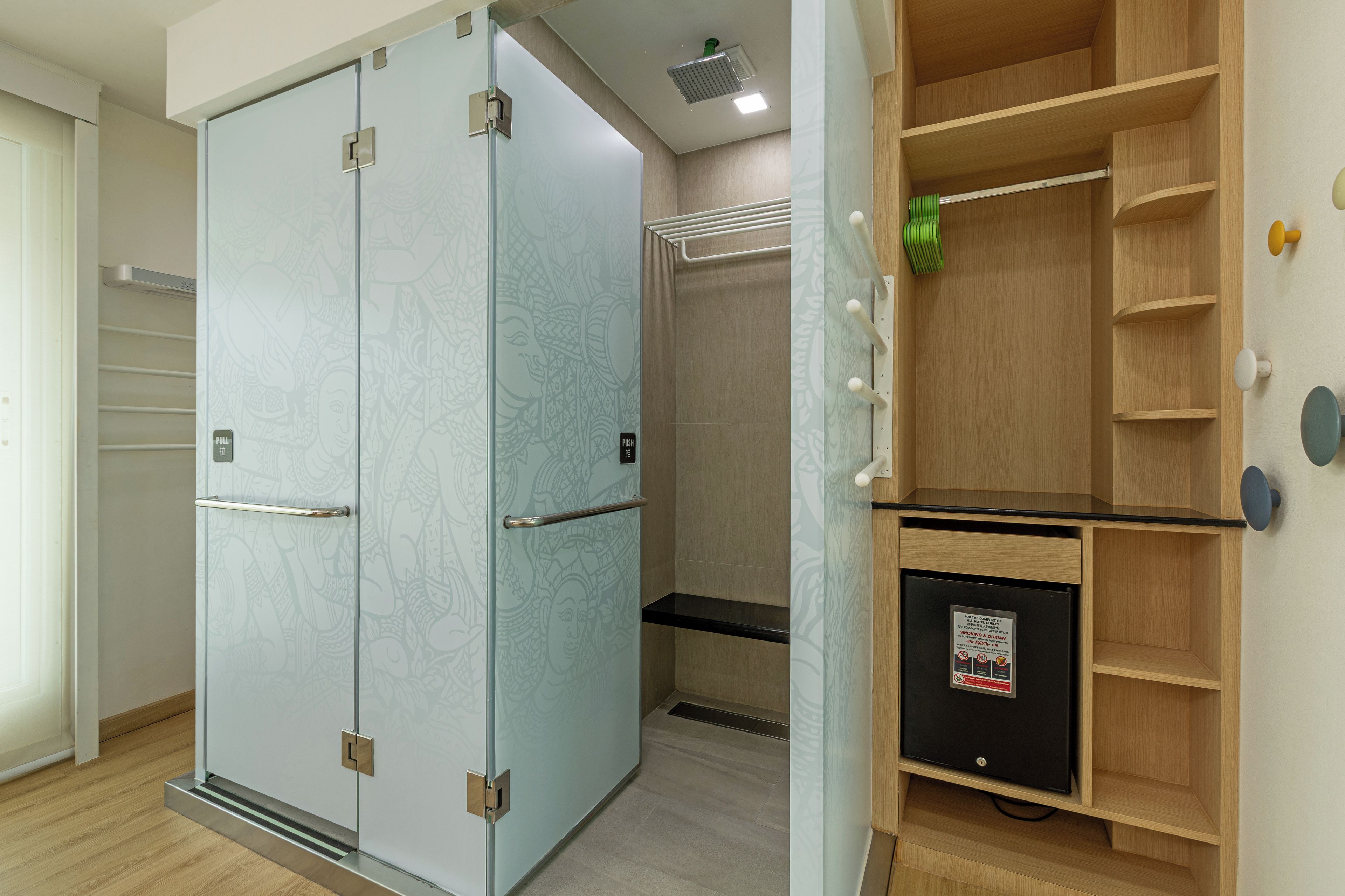 Una habitación de hotel con puerta corredera, estante empotrado y una caja de seguridad pequeña.