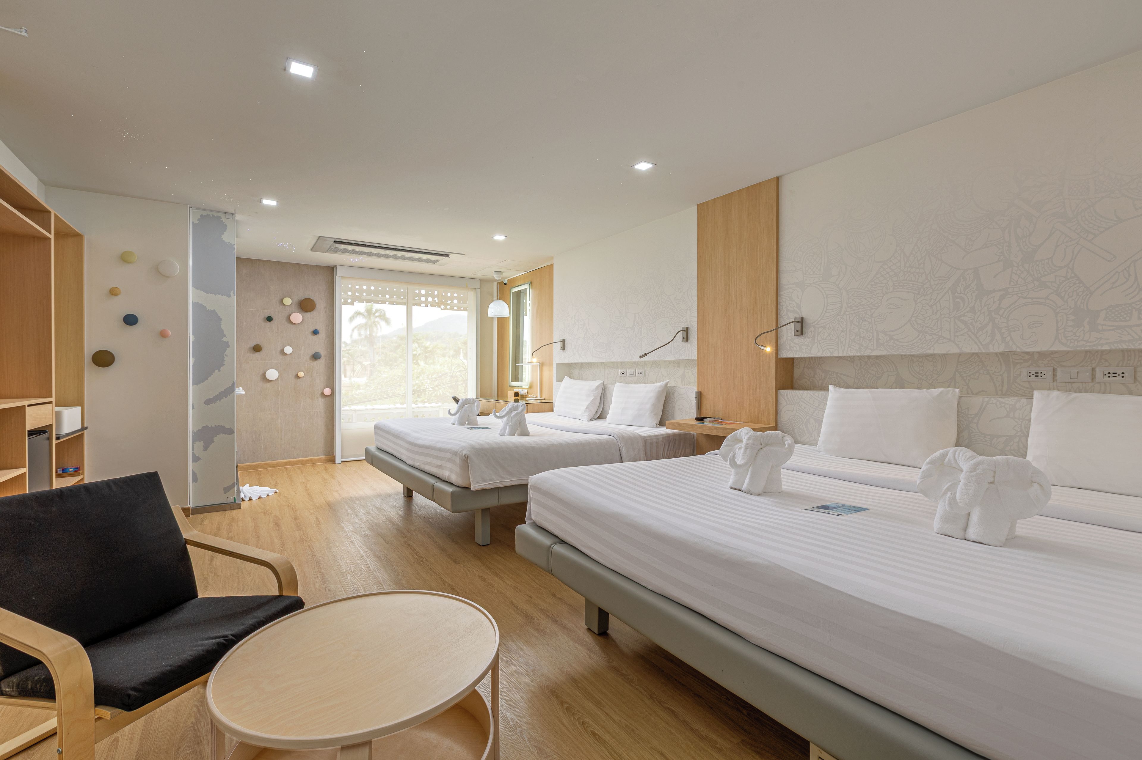 Habitación de hotel con dos camas, una mesa redonda, una silla y vistas al exterior.