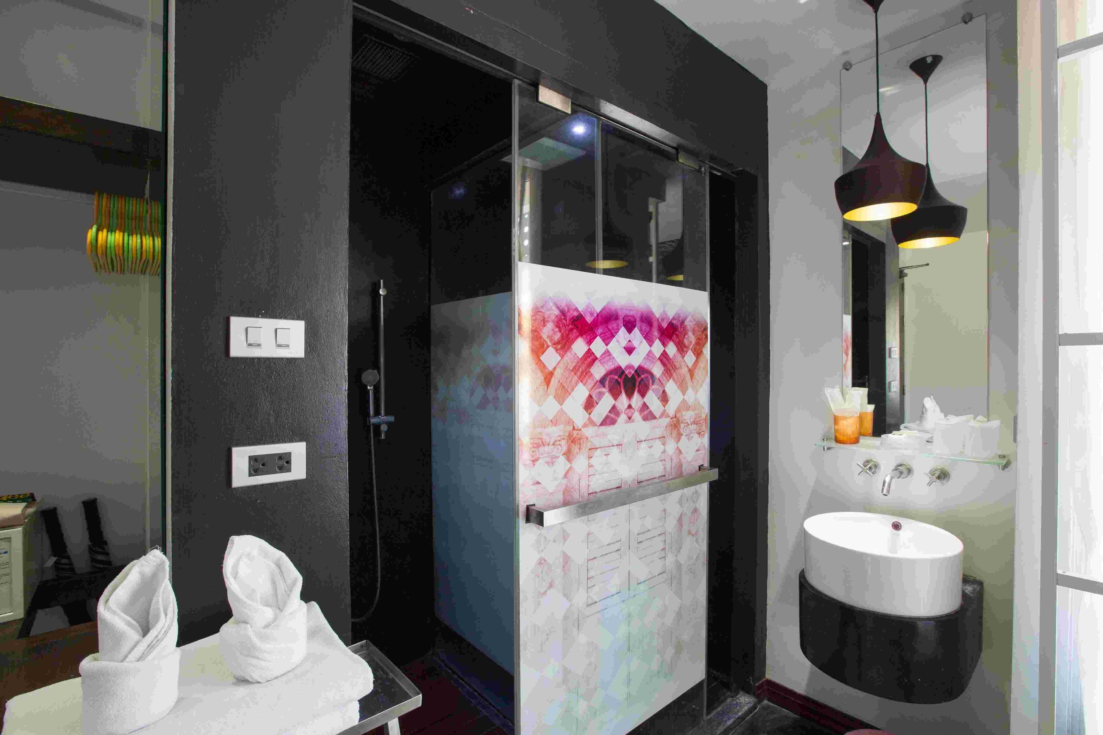 A modern bathroom with a glass shower enclosure, a white sink, and a pendant light.