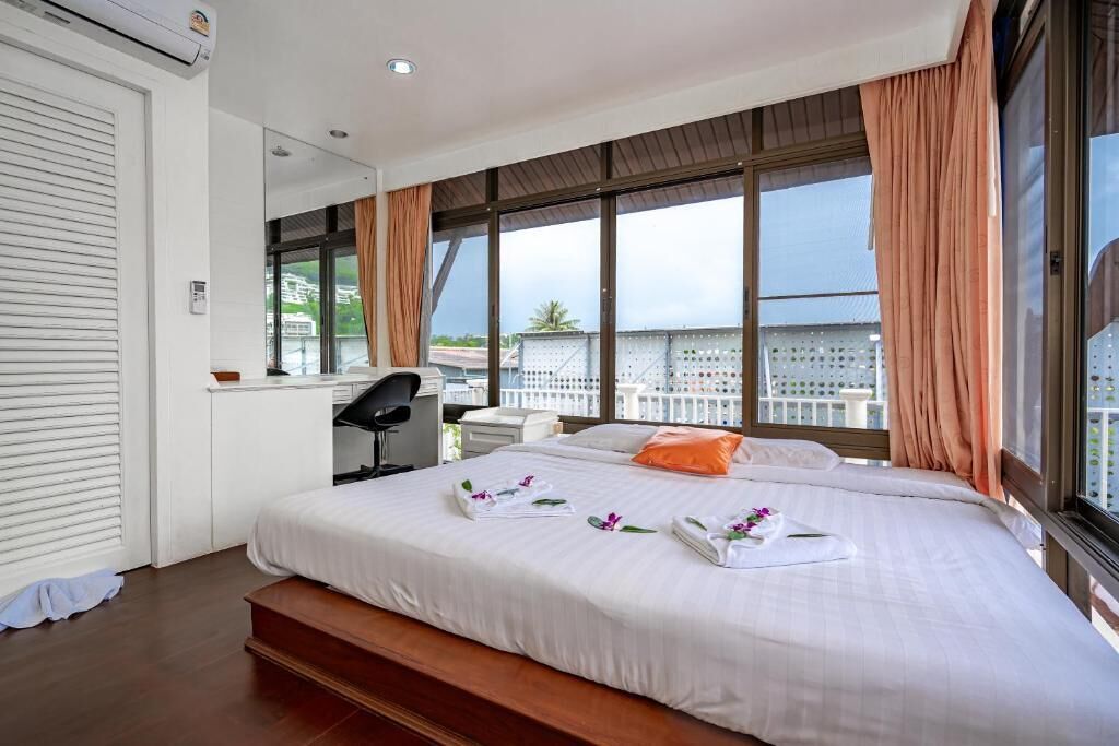 Een hotelkamer met een groot bed, een bureau en uitzicht op de stad door grote ramen.
