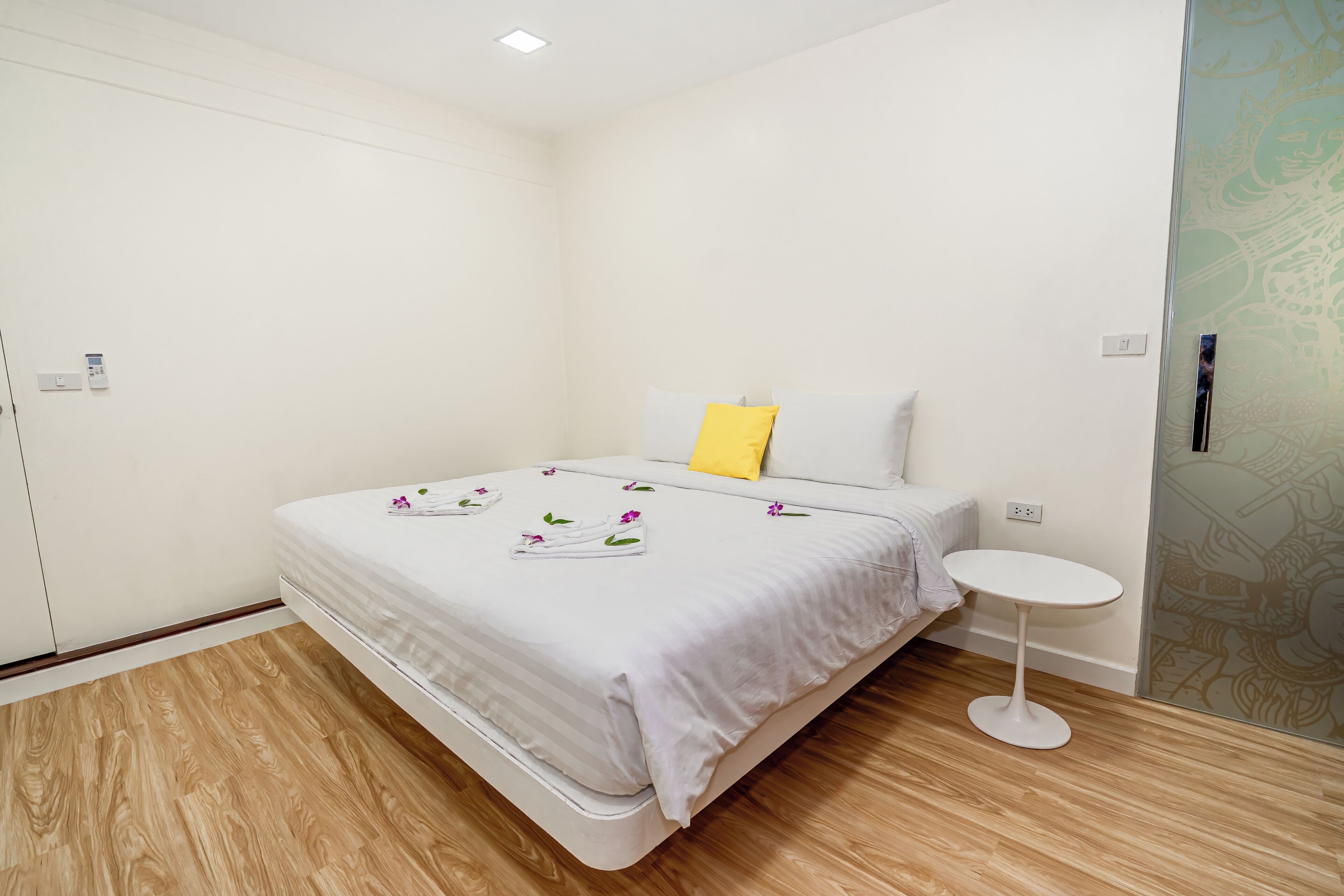 Une chambre à coucher comprenant un lit, une table de chevet et un mur agrémenté d’un panneau décoratif.