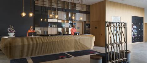 A modern reception area with a wooden reception desk, hanging pendant lights, and a visible spa room sign.