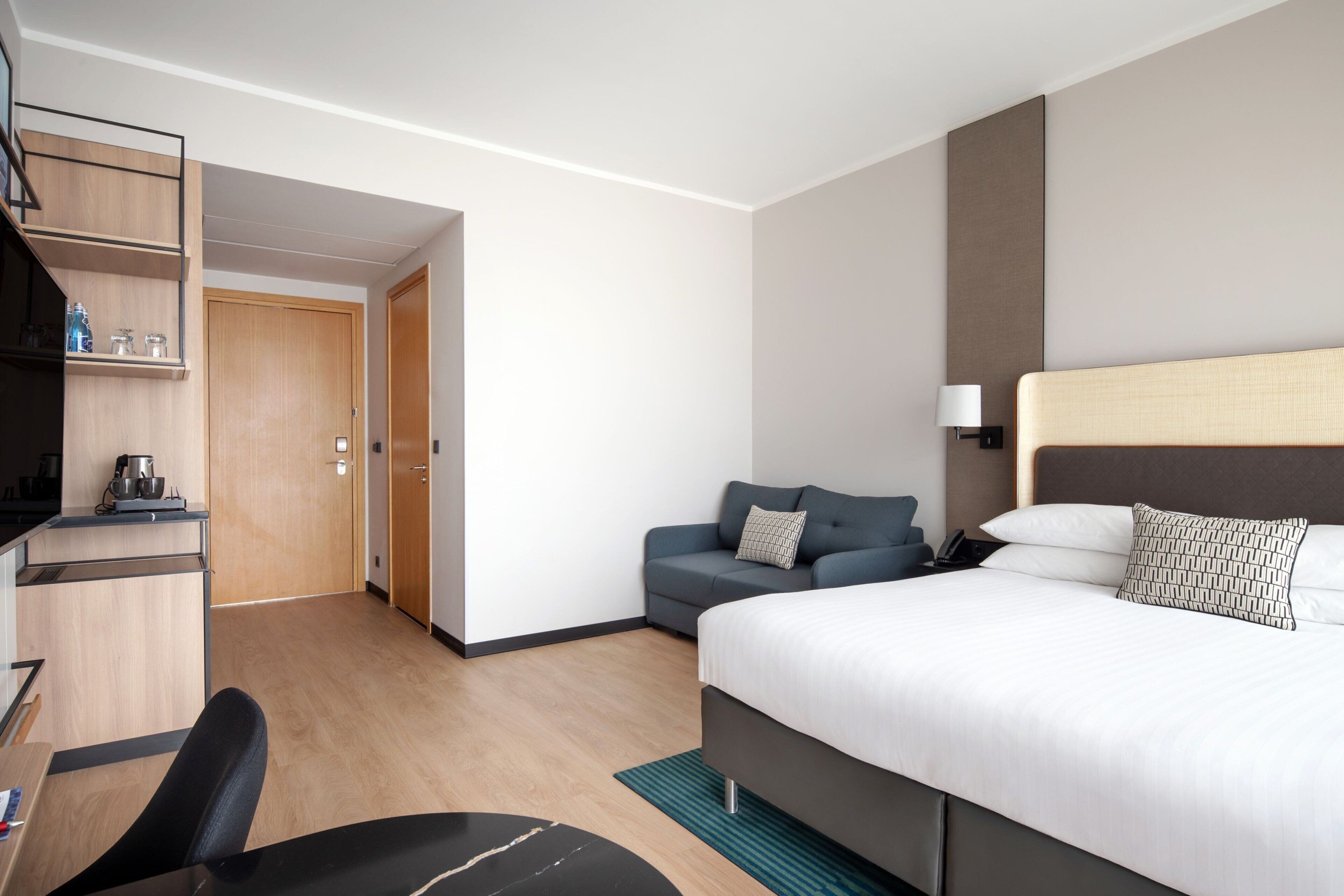 Une chambre d’hôtel comprenant un lit, un bureau, une chaise, un canapé et une armoire.