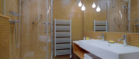 A modern bathroom with a large sink, mirror, and shower area.