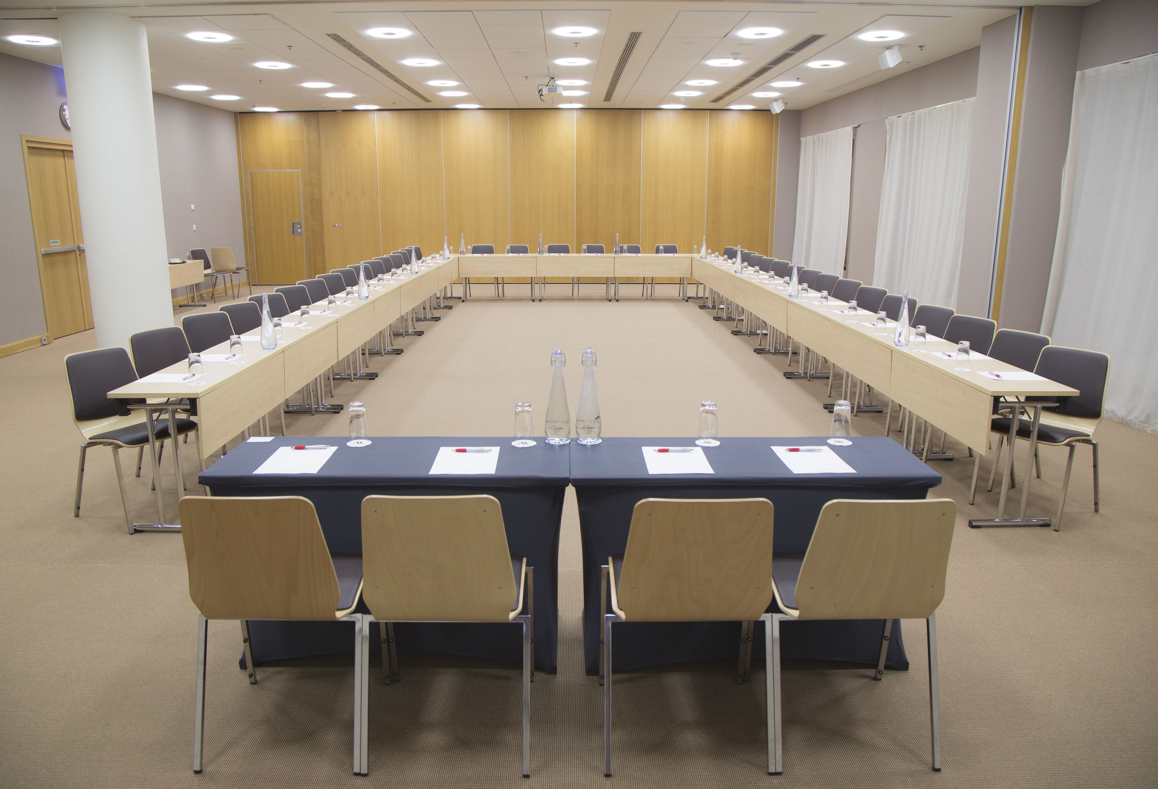 Une salle de conférence avec une longue table, des chaises et des plaques nominatives.