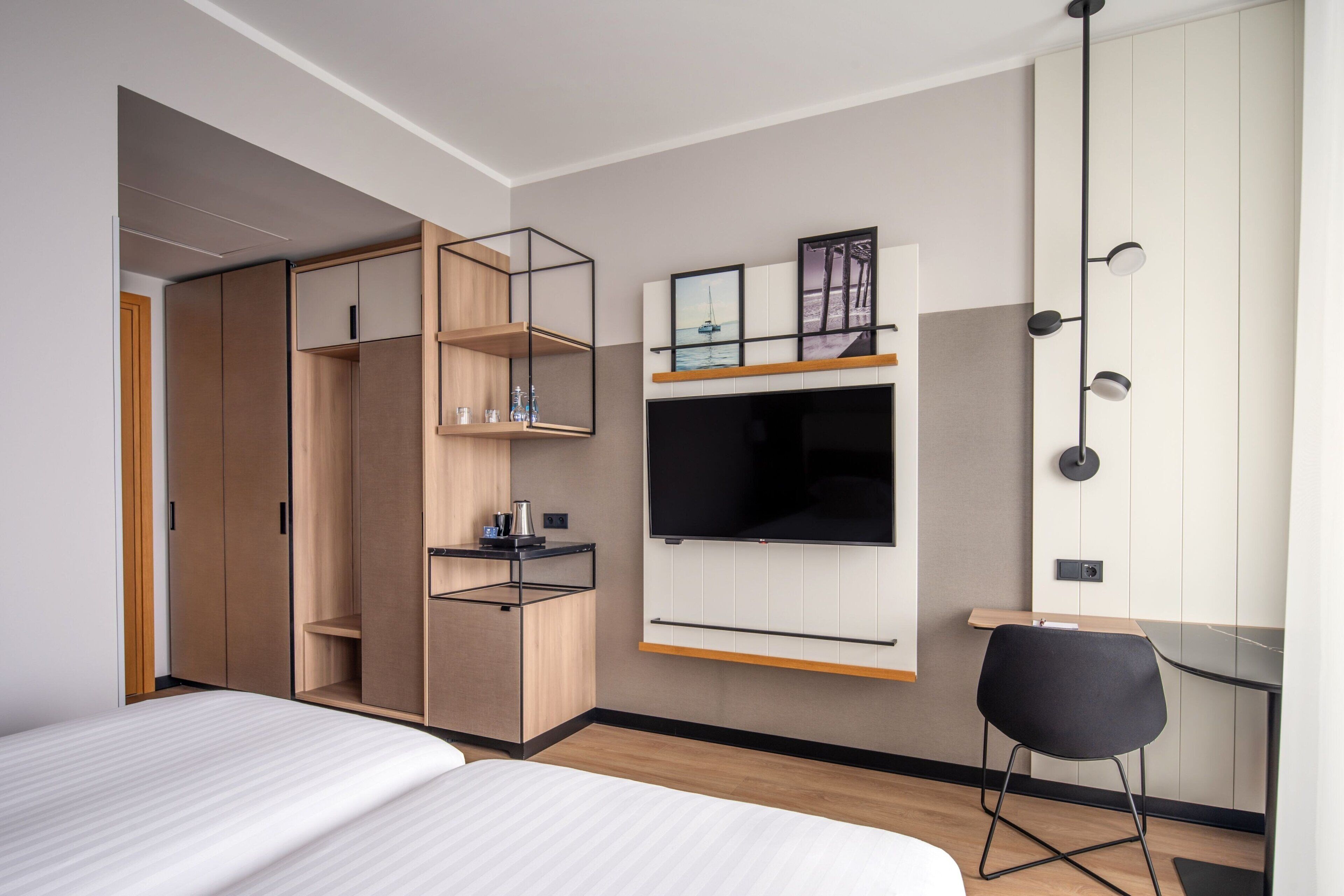 Une chambre d’hôtel moderne équipée d’un lit, d’une télévision, d’un bureau et d’une armoire.