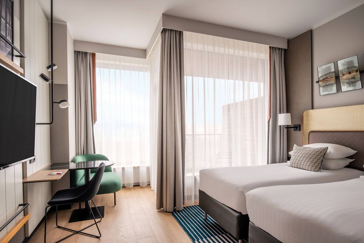 Ein Hotelzimmer mit Bett, Schreibtisch, Stuhl und Fernseher.