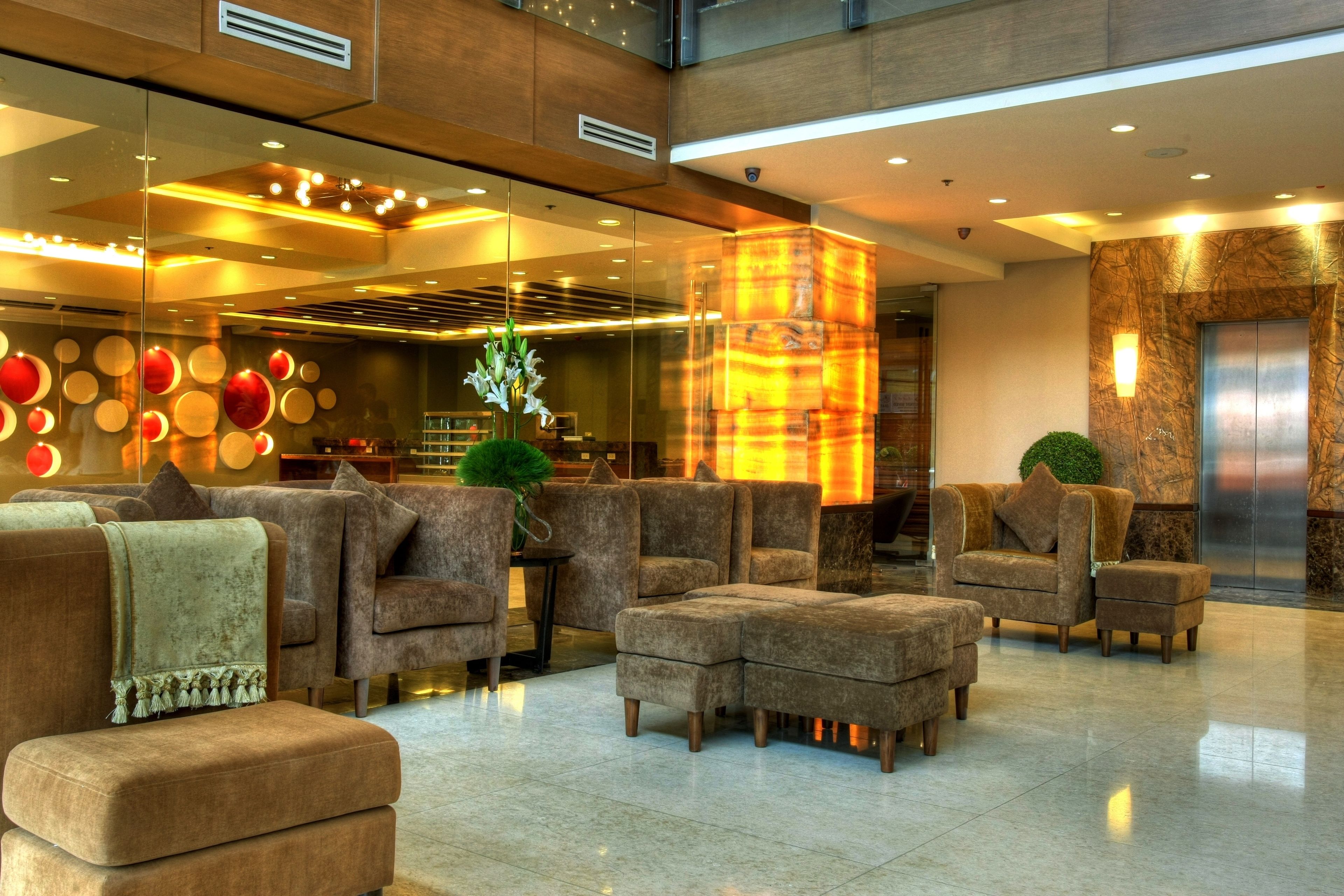 Un lobby moderno con asientos cómodos, una pared de vidrio con luces decorativas y una pared de acento de mármol.