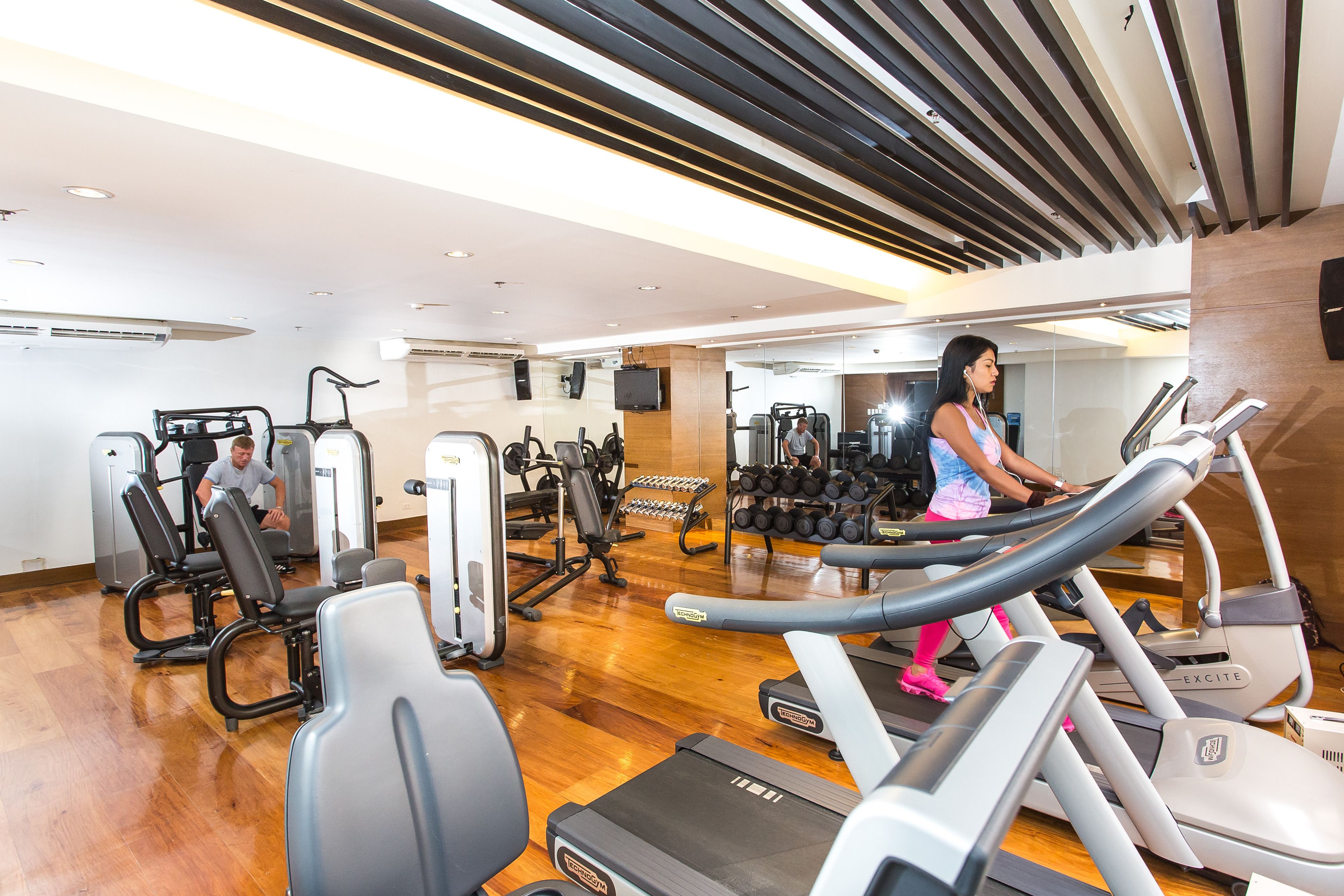 A gym with treadmills, weight machines, and a mirrored wall.