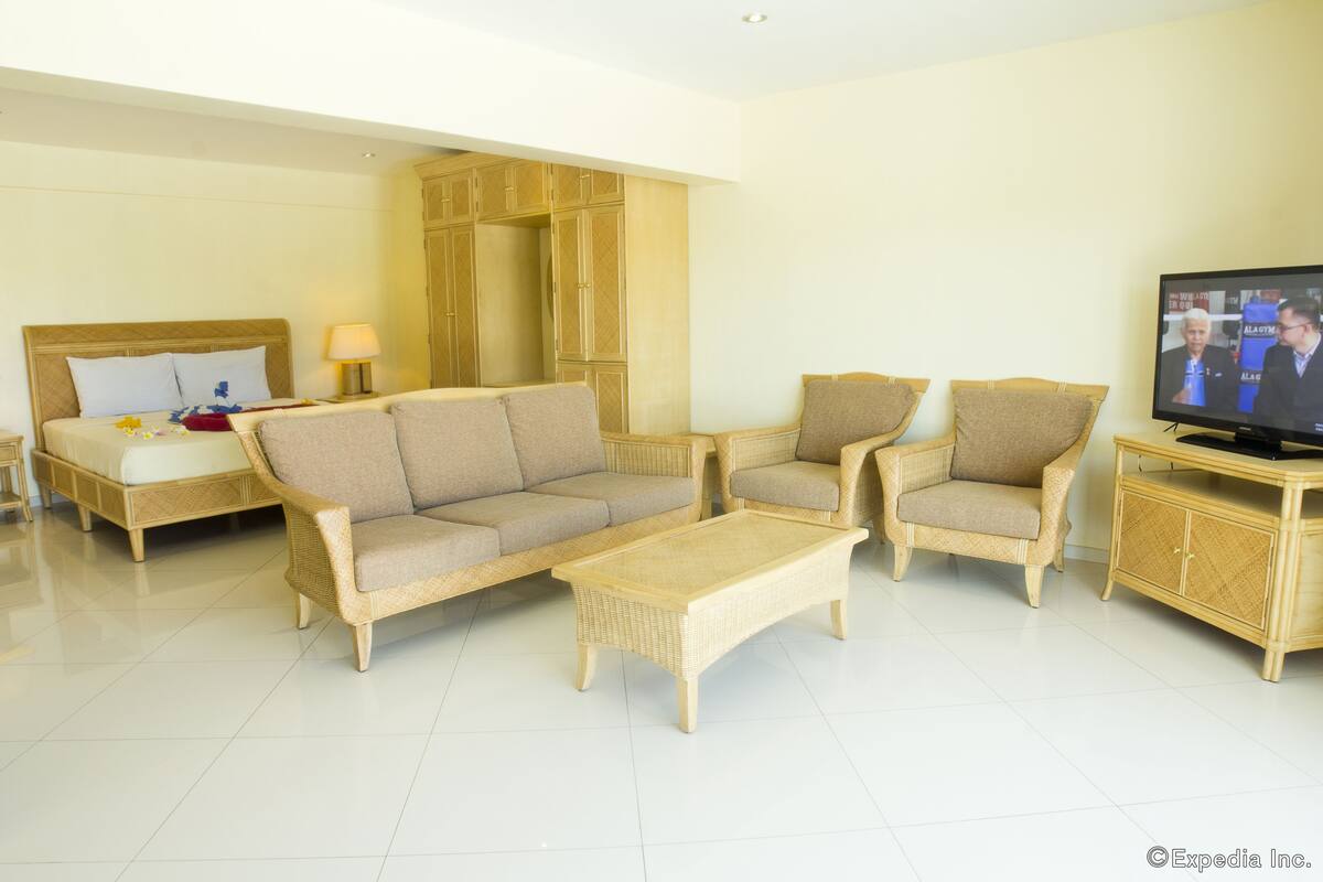 Habitación de hotel con cama, dos sofás, una mesa de centro, televisión y armario.