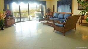 A spacious living room with a balcony, a television, wicker furniture, and a large window with curtains. - Lingganay Boracay Hotel Resort (Boracay Island)