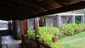 A covered outdoor area with stone walls, wooden doors, and potted plants. - Casa D'Avó Beatriz (Santa Cruz)
