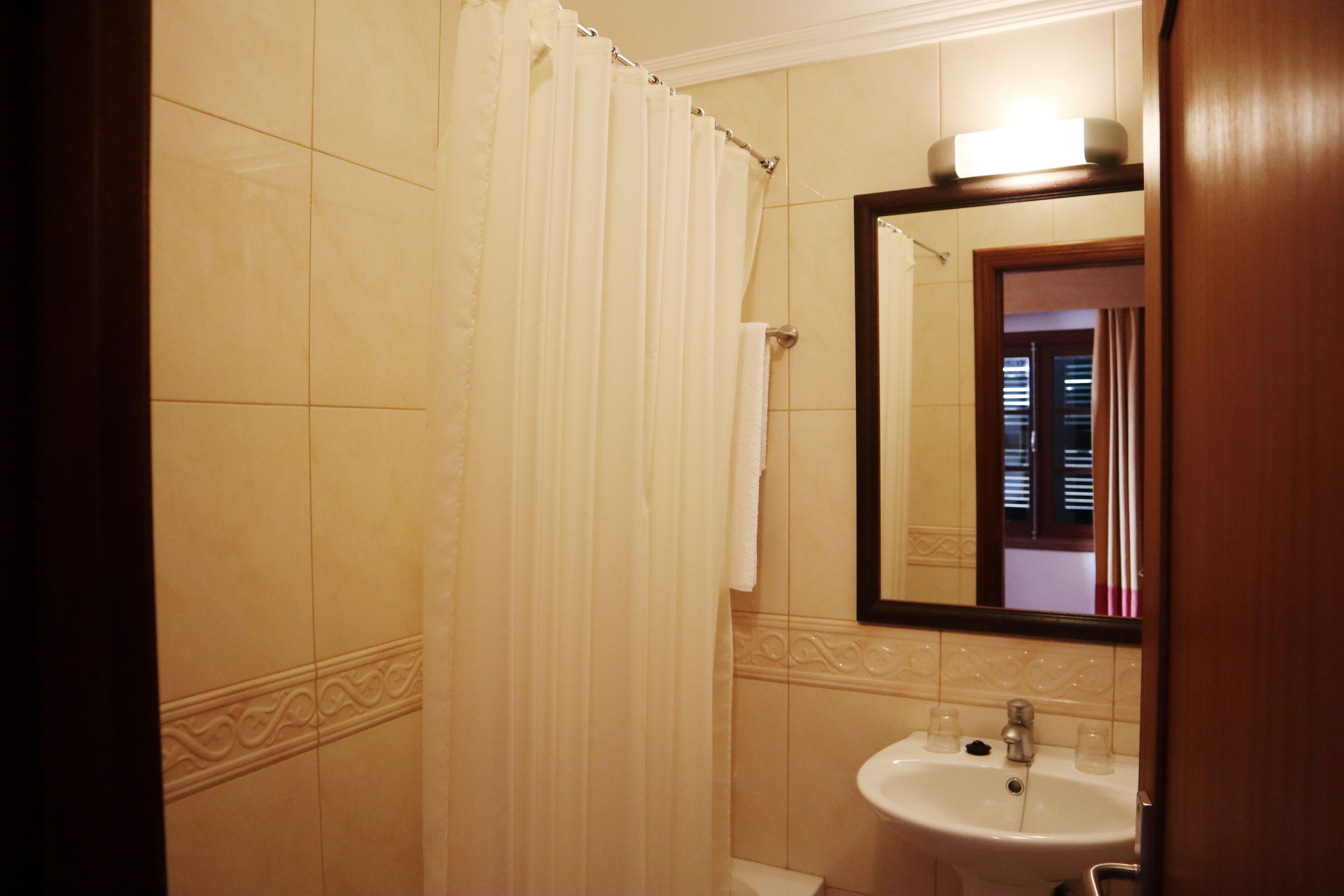 A bathroom with a shower curtain, a sink, and a mirror.