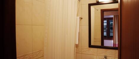A bathroom with a shower curtain, a sink, and a mirror.