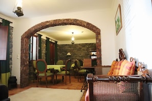 A dining area with a stone archway, wooden furniture, and a chandelier. - Casa D'Avó Beatriz (Santa Cruz)