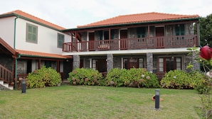 A two-story house with a stone facade, a red-tiled roof, and a wooden balcony. - Casa D'Avó Beatriz (Santa Cruz)