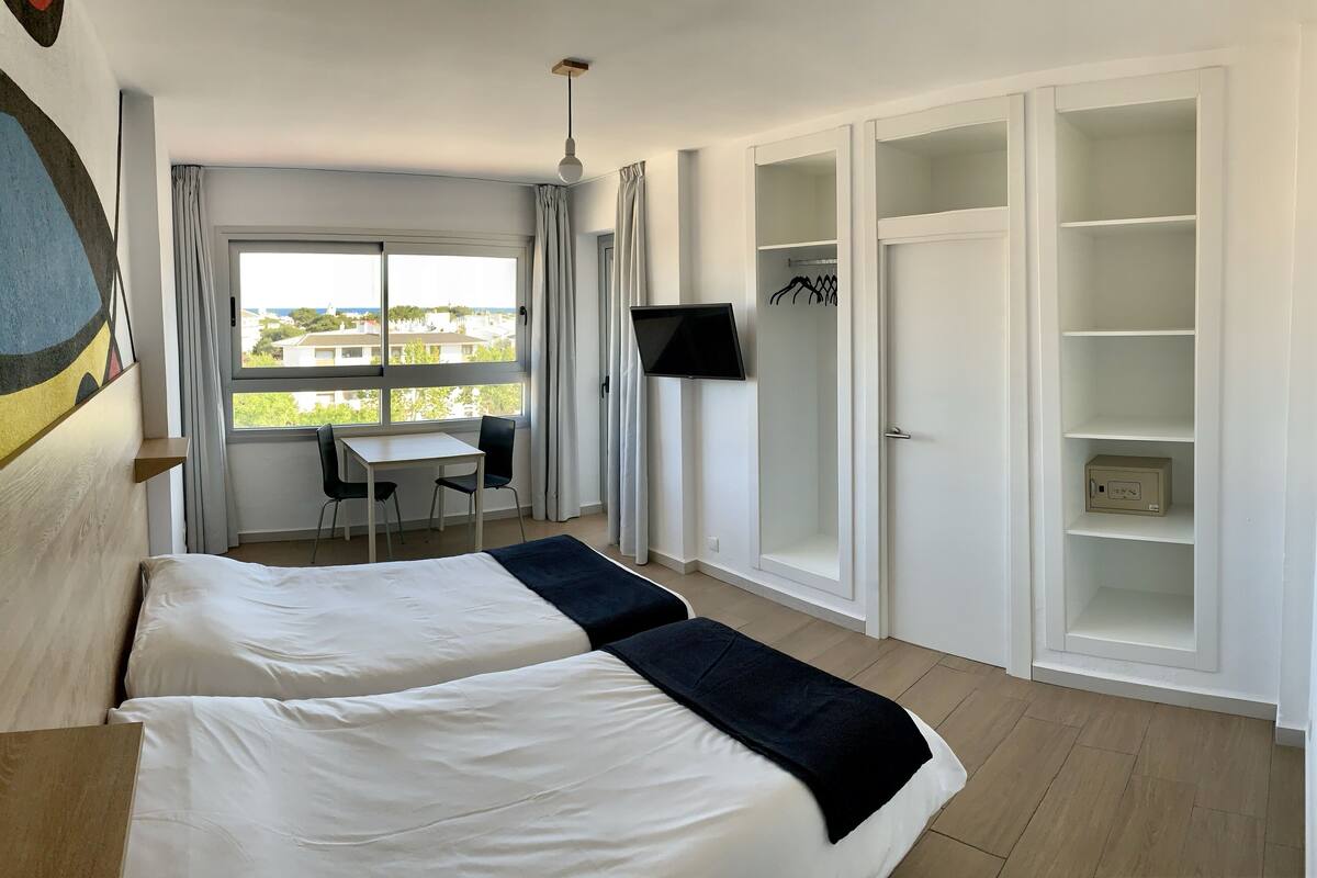 Una habitación de hotel con dos camas, un escritorio, un televisor y un armario.