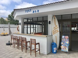 Un bar tiki con decoración de tabla de surf, asientos al aire libre y un anuncio de Nestlé.