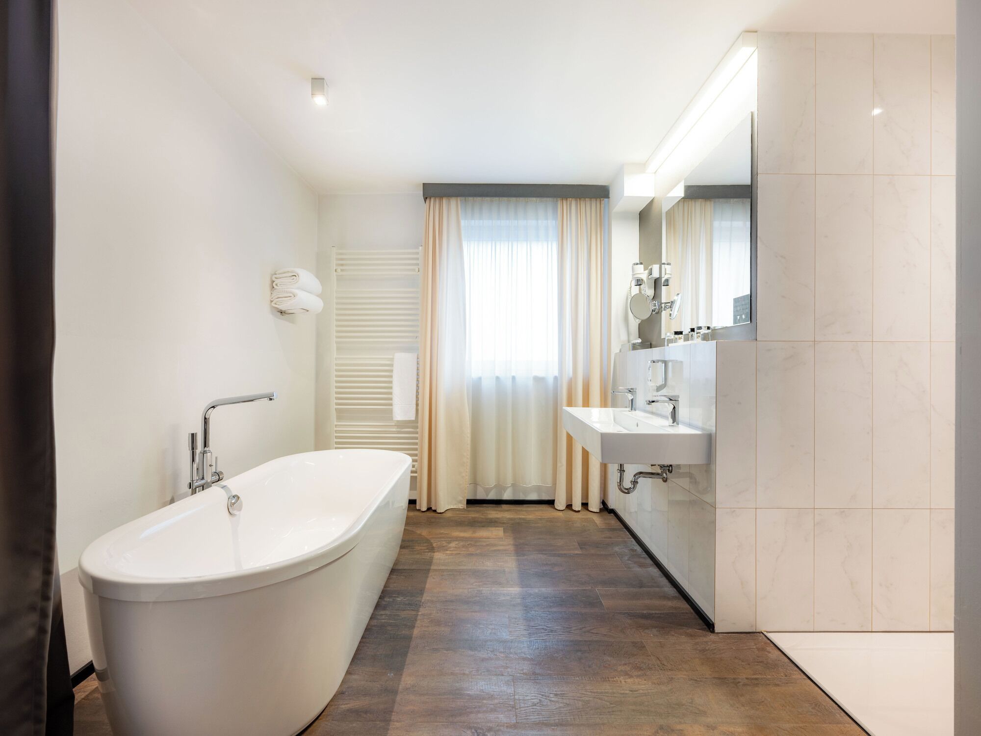 Un baño moderno con una bañera independiente, un tocador con espejo y zona de ducha.