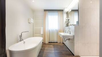 Un baño moderno con una bañera independiente, un tocador con espejo y zona de ducha.