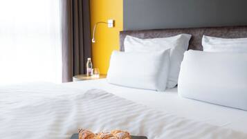Une chambre d’hôtel avec un lit, une table de chevet, une lampe et une fenêtre avec des rideaux.