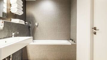 A modern bathroom with a large bathtub, a vanity with a mirror, and a towel rack.