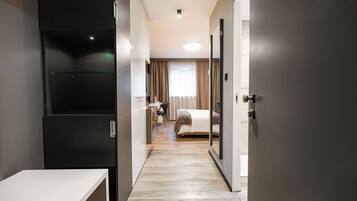 A hotel corridor with a bed, a desk, and a wardrobe.