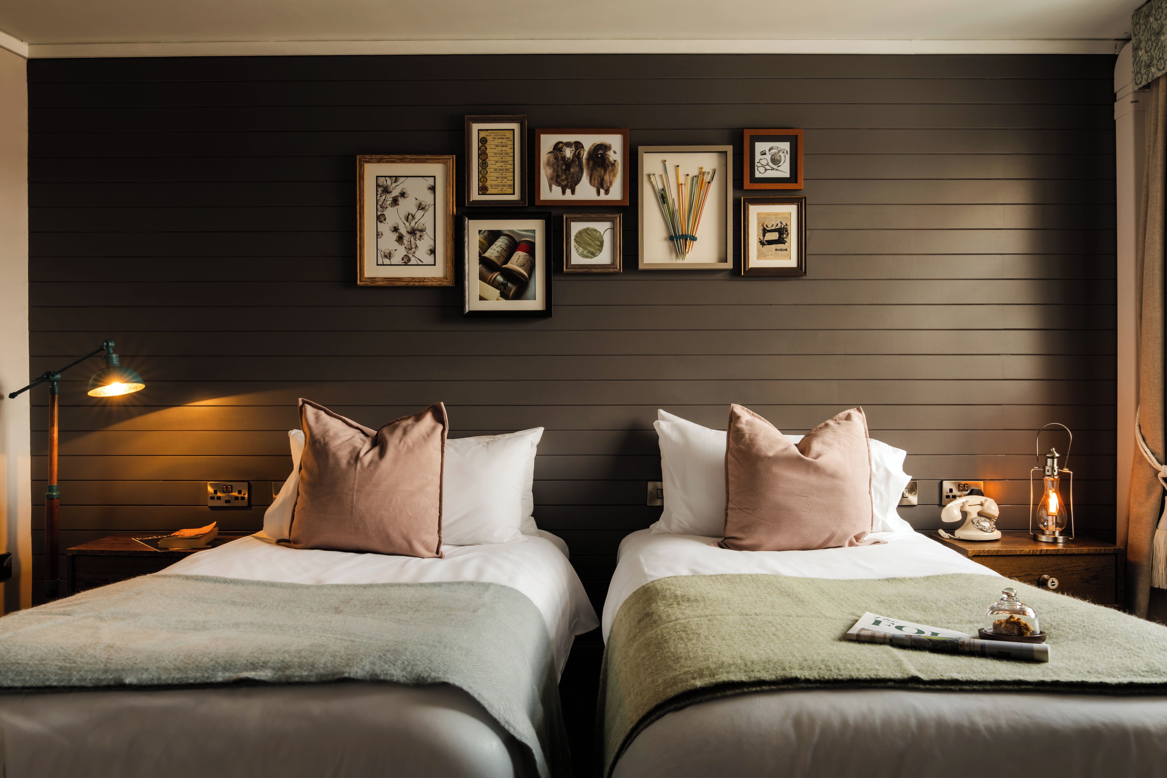 Une chambre d’hôtel avec deux lits, une table de chevet avec une lampe, un téléphone et une lanterne.