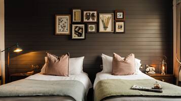 A hotel room with two beds, a nightstand with a lamp, a telephone, and a lantern.