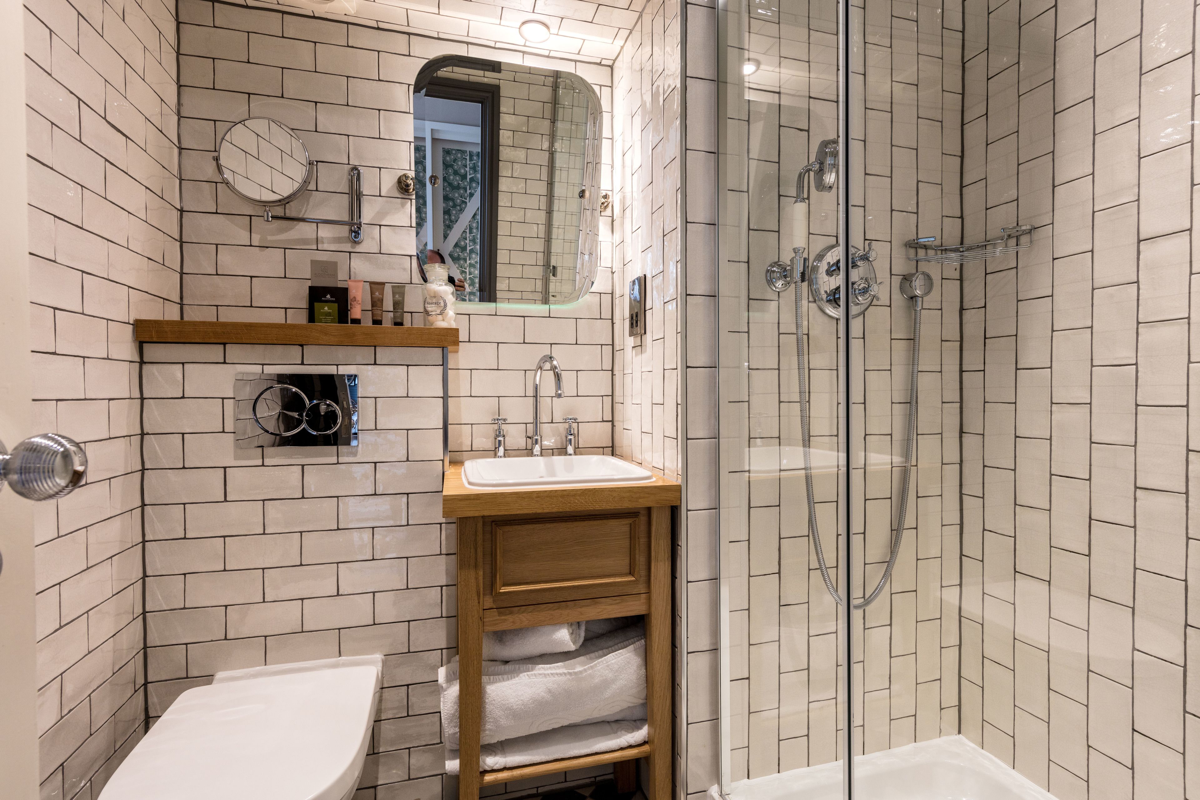 Un baño moderno con lavamanos, espejo y ducha blancos.