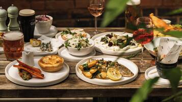A wooden table with various dishes, glasses, and a brick wall in the background.