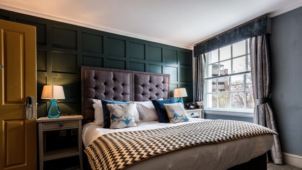 Un dormitorio con una cama grande, dos mesitas de noche y una ventana con cortinas.