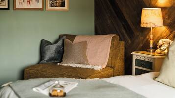 A cozy room with a bed, a nightstand with a lamp, and a wall with framed pictures.