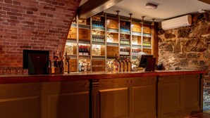 Zona de bar con pared de ladrillo, estantes de madera con botellas y una barra con grifos.
