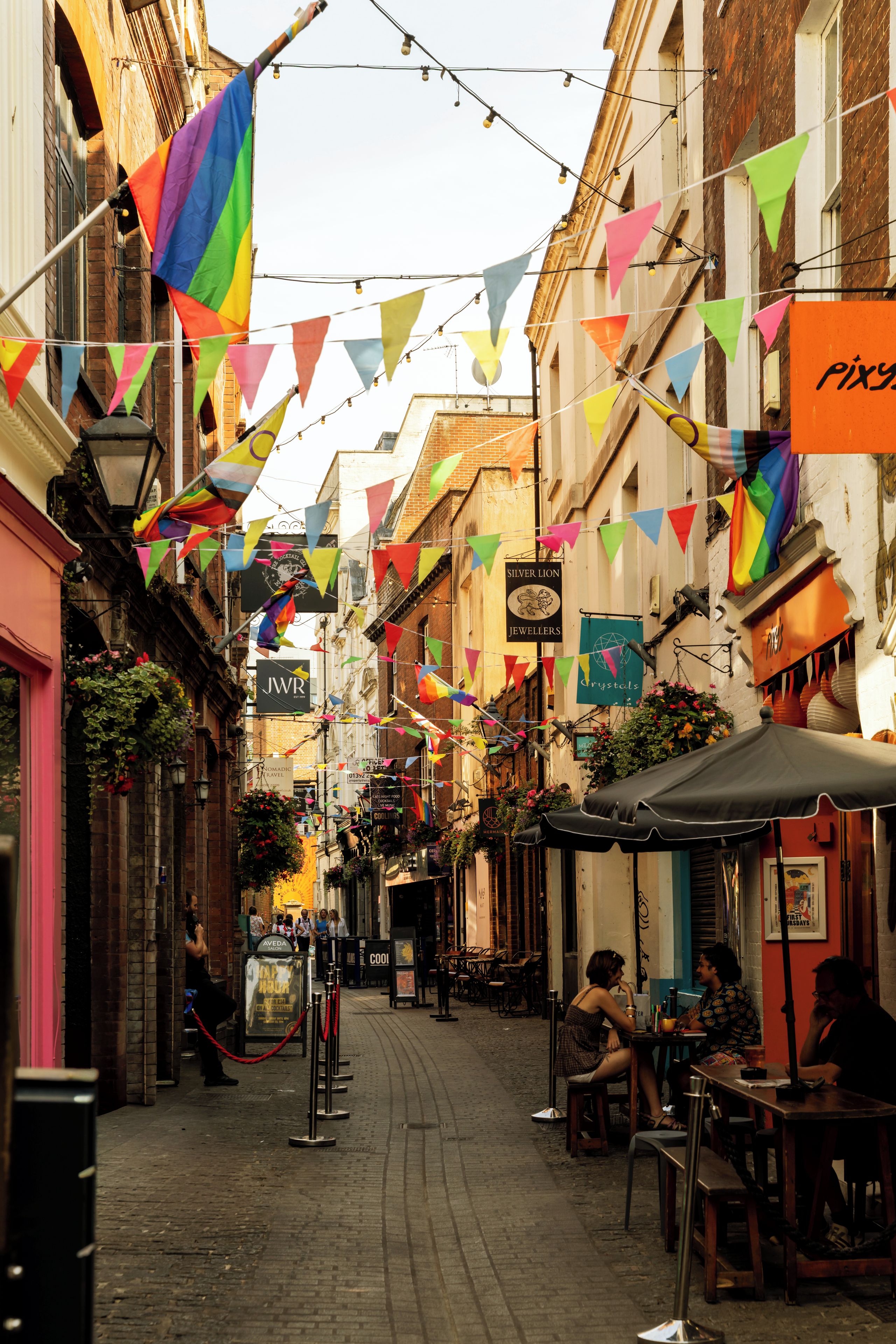 Una calle estrecha flanqueada por edificios, algunos con letreros de tiendas y restaurantes.