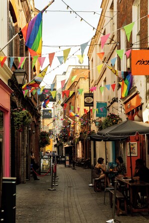 Una calle estrecha flanqueada por edificios, algunos con letreros de tiendas y restaurantes.