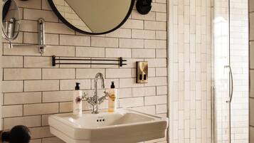 A bathroom with a white sink, a mirror, and a shower.