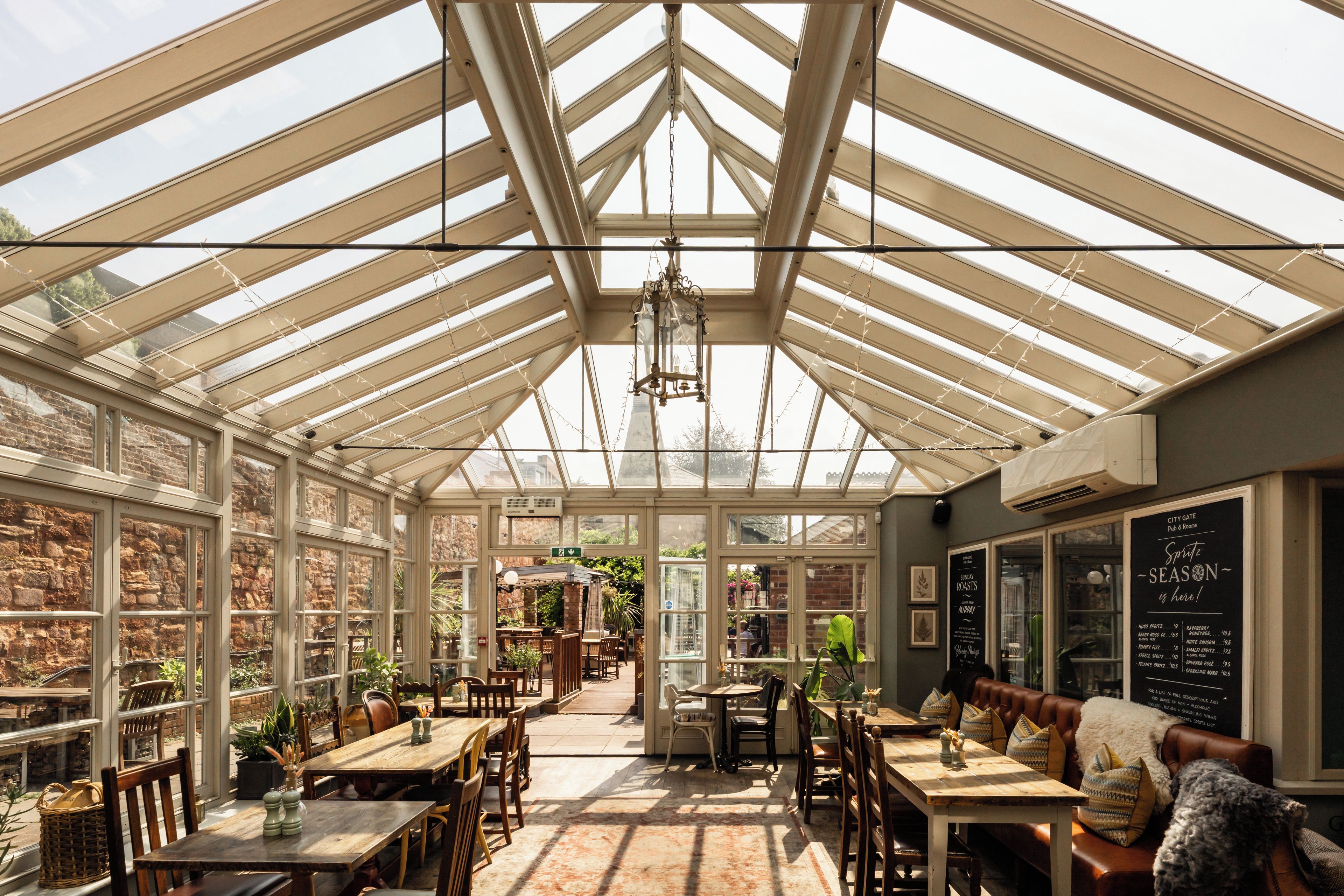 A conservatory with a high ceiling, large windows, and a central hanging light fixture.