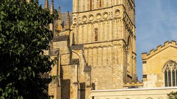 A historic building with a prominent tower and a smaller adjacent structure with tables and umbrellas.