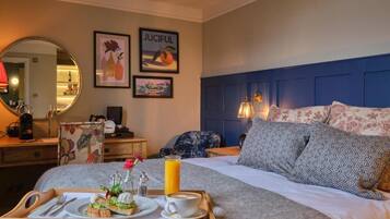 A hotel room with a bed, a bedside table, a tray with breakfast items, and artwork on the wall.