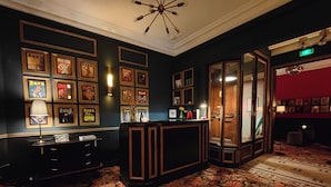 A lobby with a reception desk, framed pictures on the wall, a chandelier, and a patterned carpet.