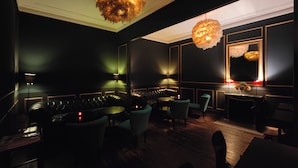 A dimly lit room with leather seating, a round table, and a large mirror.