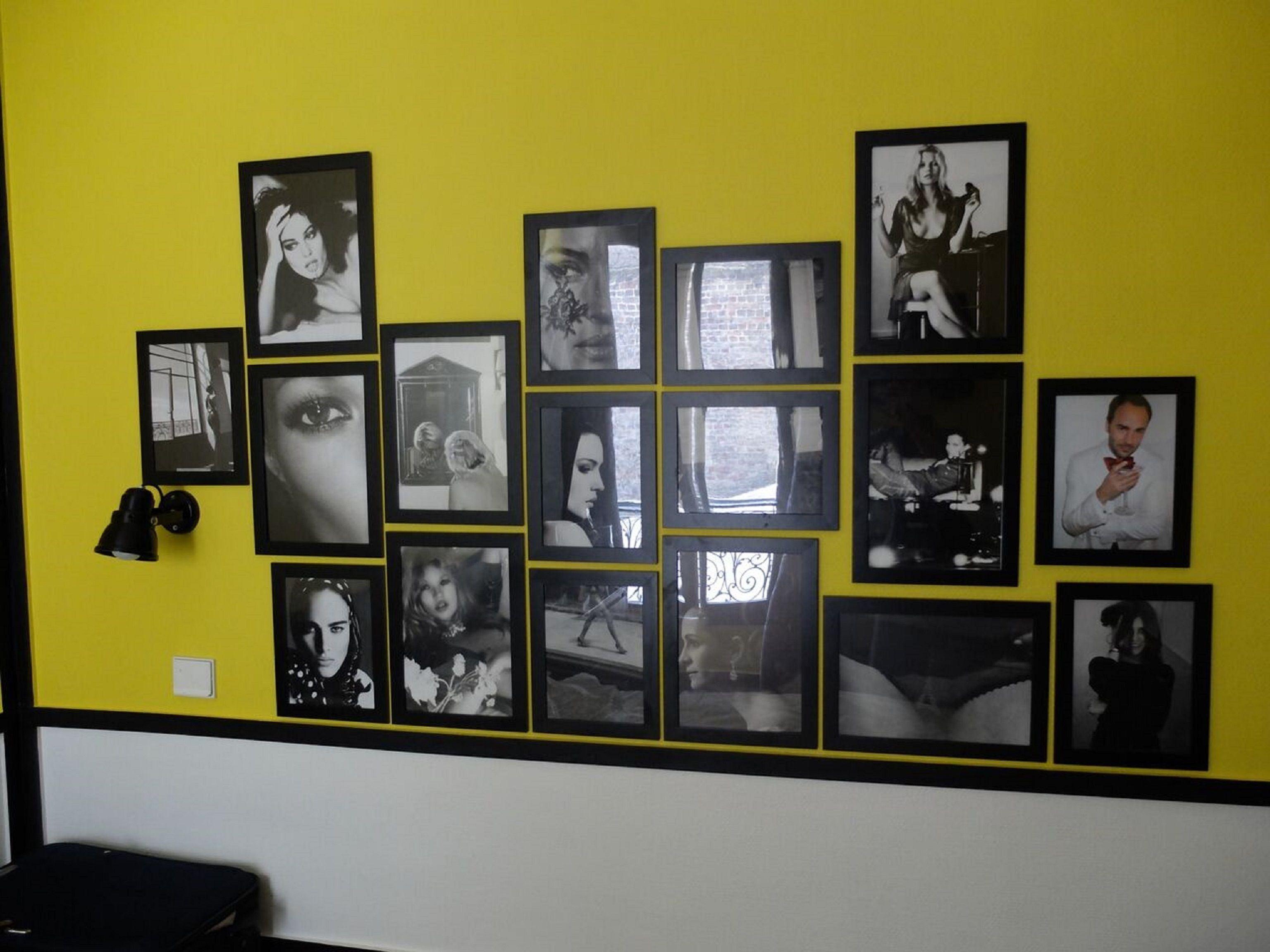 A wall with multiple framed black and white photographs arranged in a grid pattern.