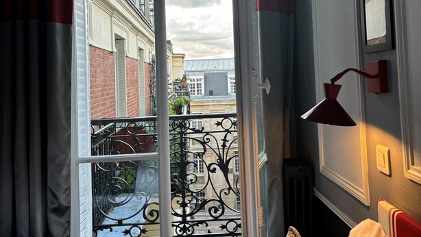 Una stanza con un'ampia finestra, una lampada rossa e vista sugli edifici.