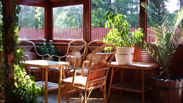 Un patio cubierto con mobiliario de mimbre y plantas en macetas.