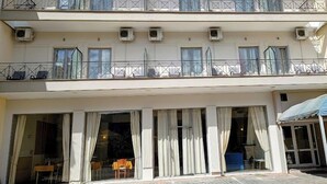 A multi-story hotel with balconies, large windows, and air conditioning units. - King Lodge (Kalabaka)