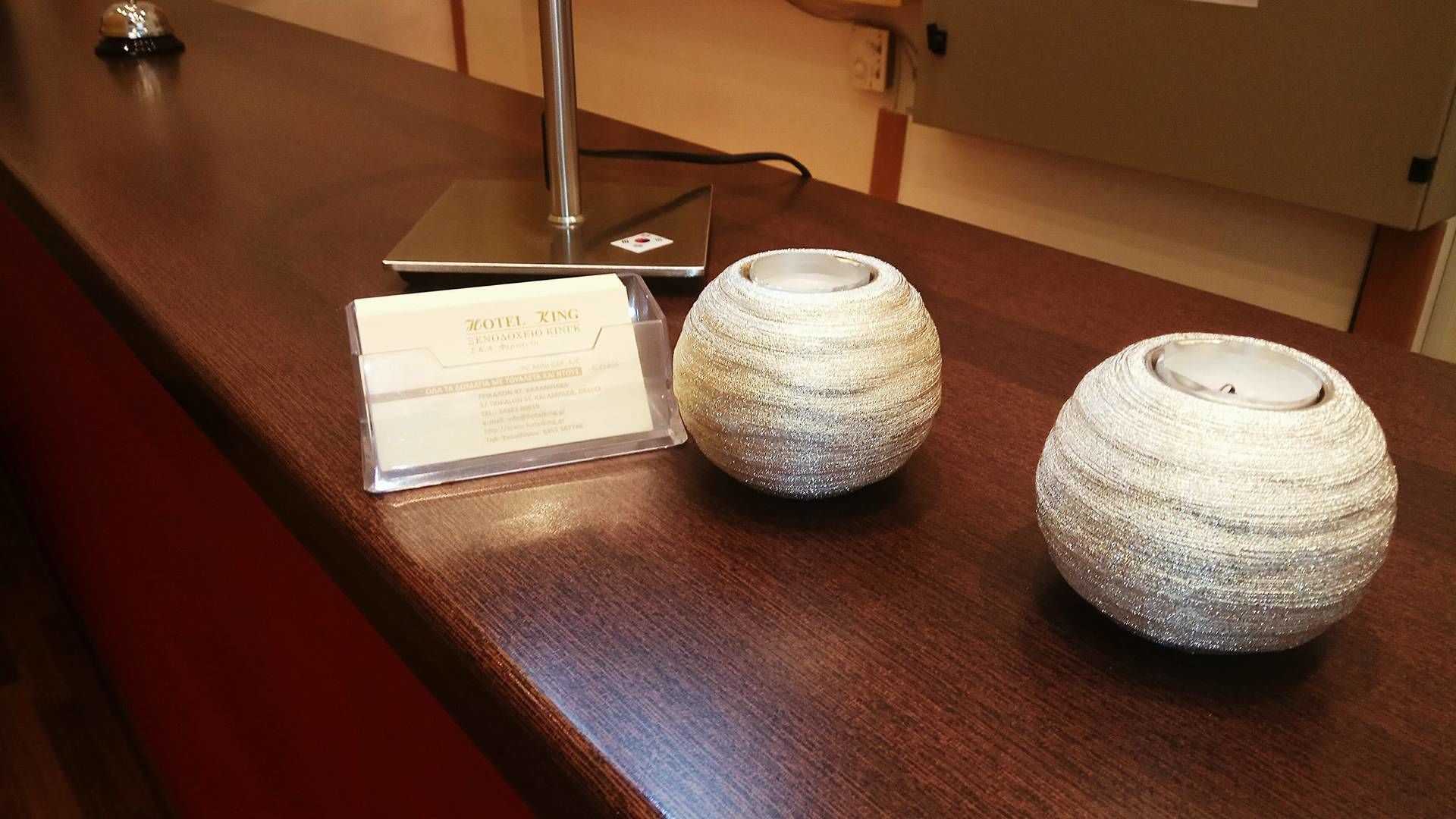 A reception desk with a laptop, a sign for HOTEL KING, and two decorative vases.