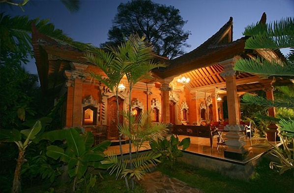 A traditional building with a covered porch, columns, and a seating area.