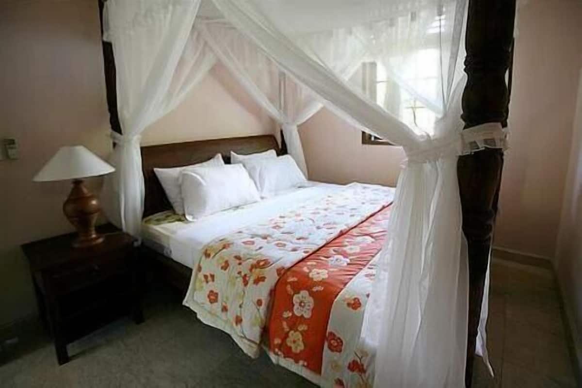 Una cama con dosel, una mesita de noche y una lámpara.